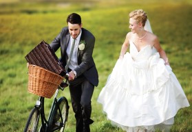 Married couple walking in the garden pushing a bicycle